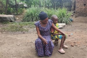 A mother sits next to her child on a small bench.