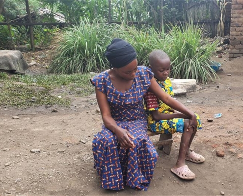 A mother sits next to her child on a small bench.