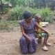A mother sits next to her child on a small bench.